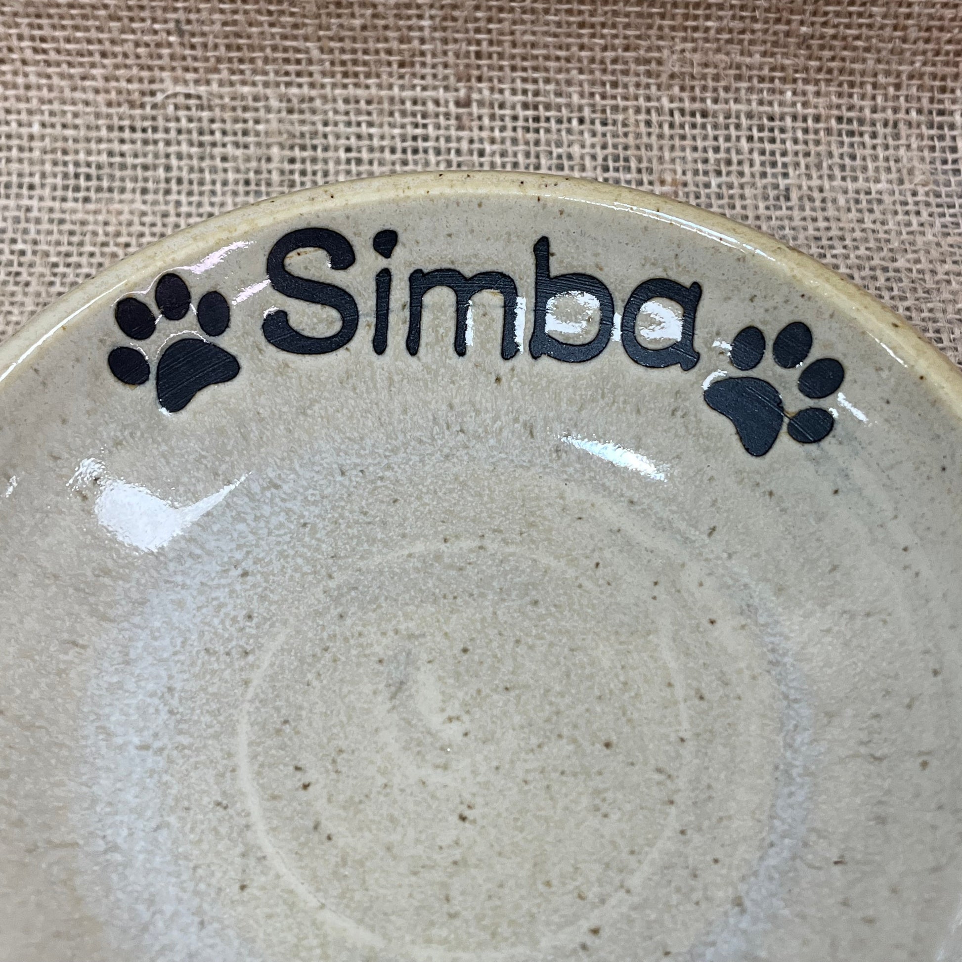 Ceramic plate with 'Simba' and paw prints on a textured surface