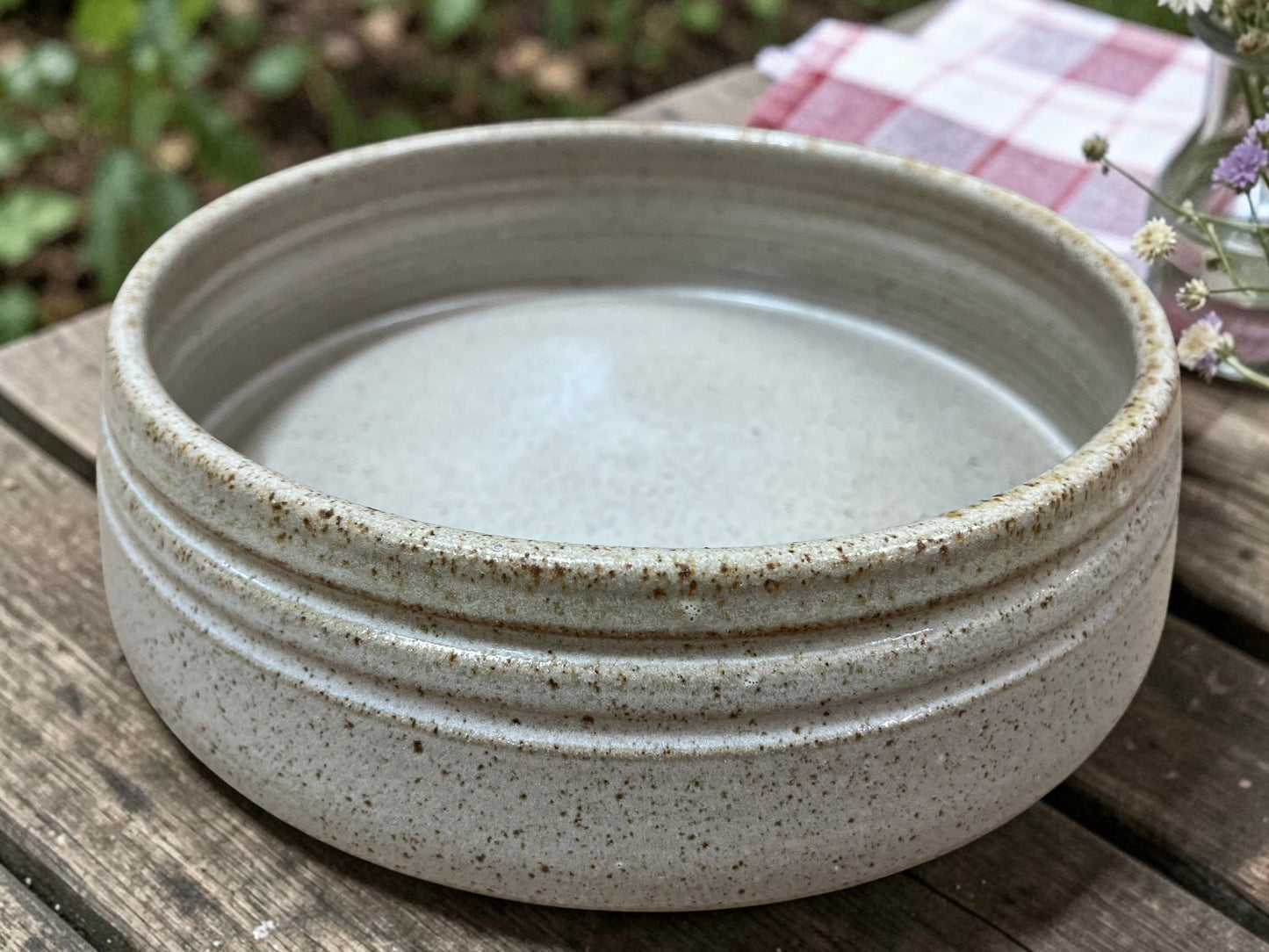 Speckled ceramic bowl on a wooden surface with a natural background