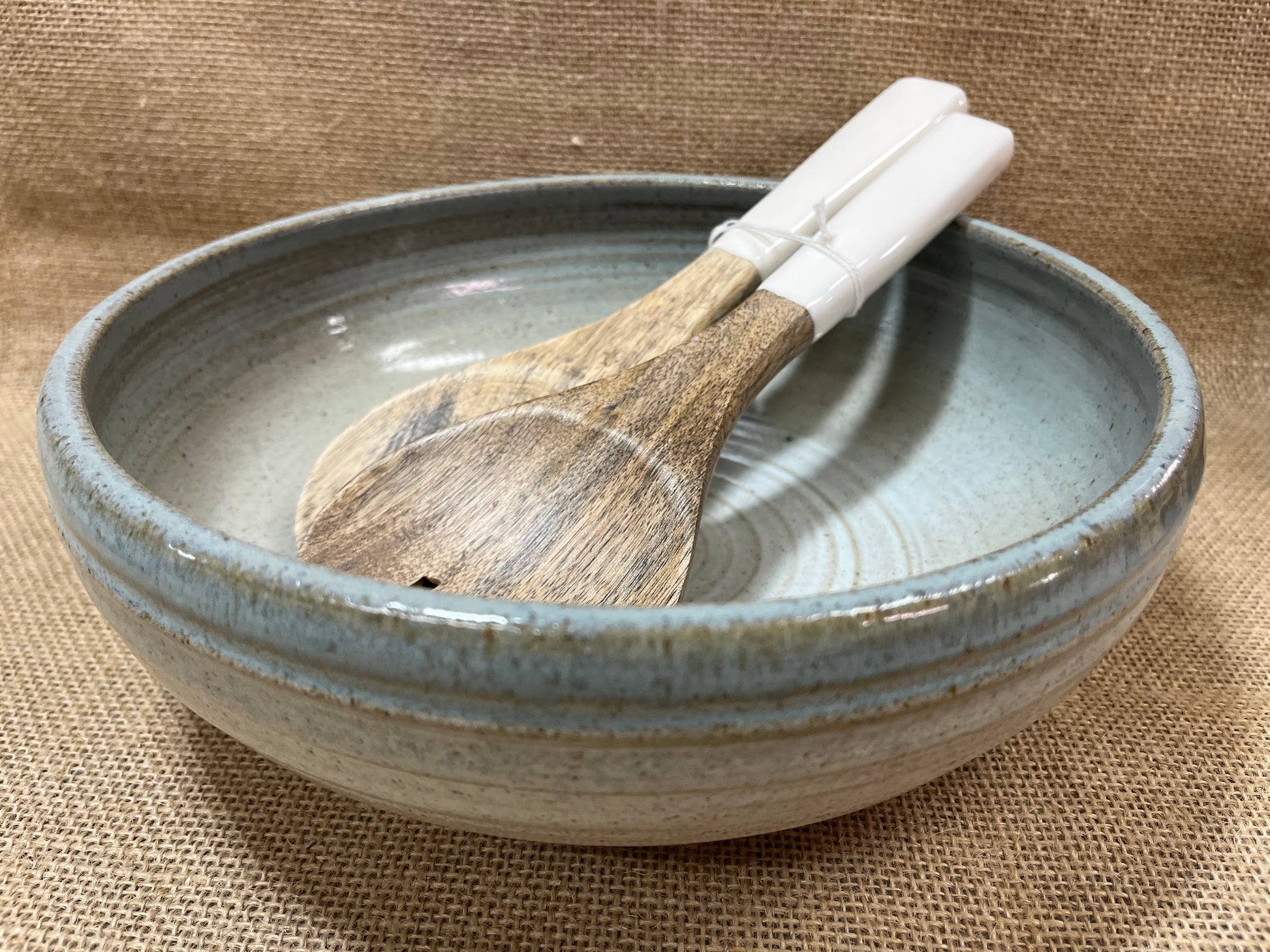Ceramic bowl with wooden spoon on a textured fabric background