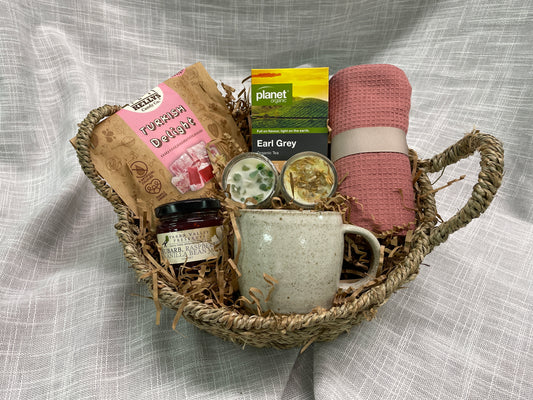 Seagrass basket featuring pottery mug, turkish delight, jam, tea, tea towel and 2 miniature candles.