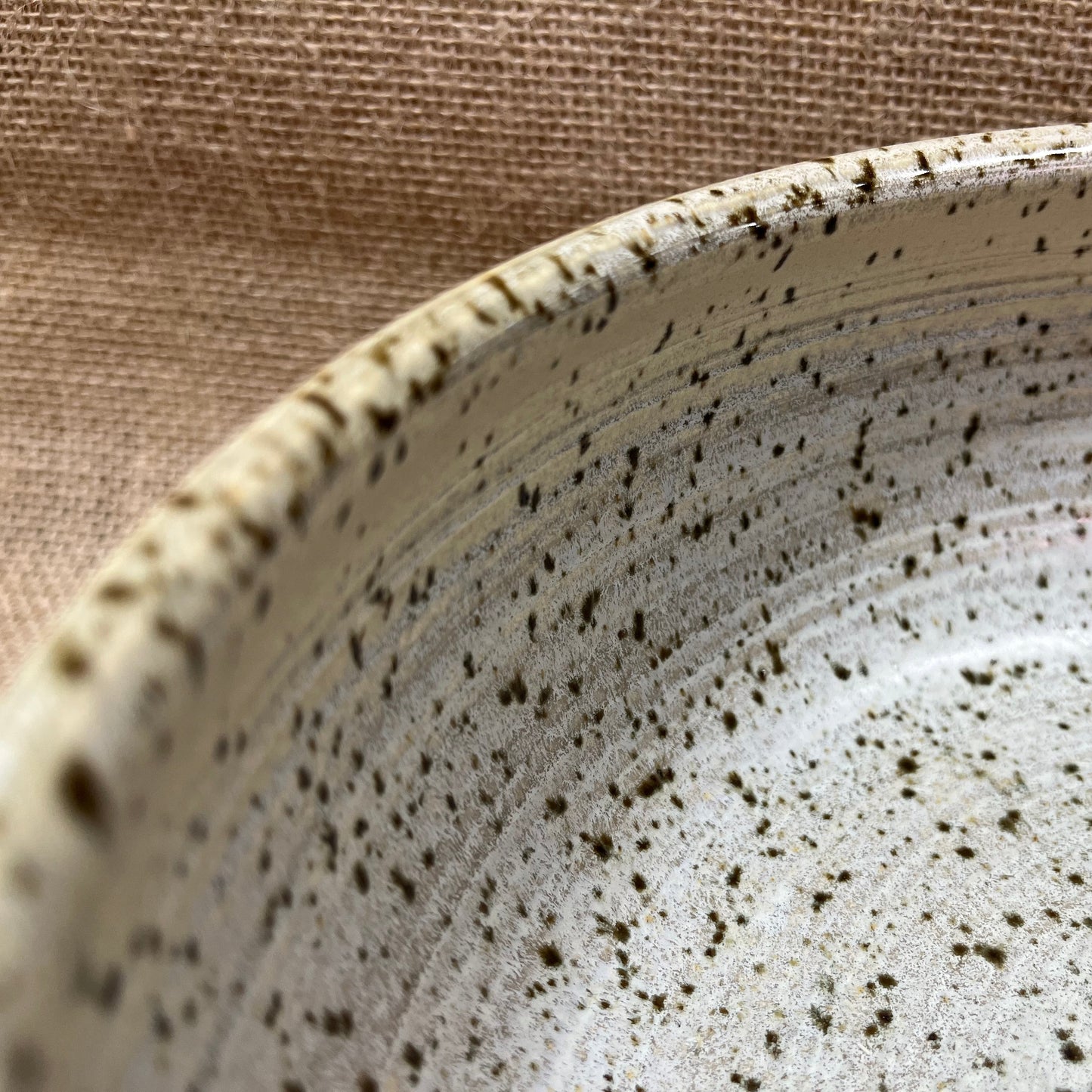 Close-up of a ceramic bowl with speckled pattern on a beige background