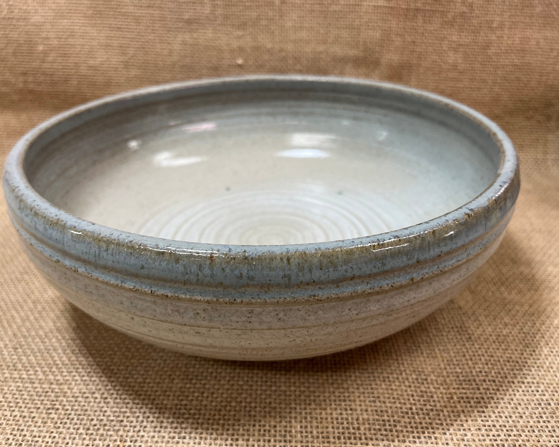 Ceramic bowl with blue rim on a brown fabric background