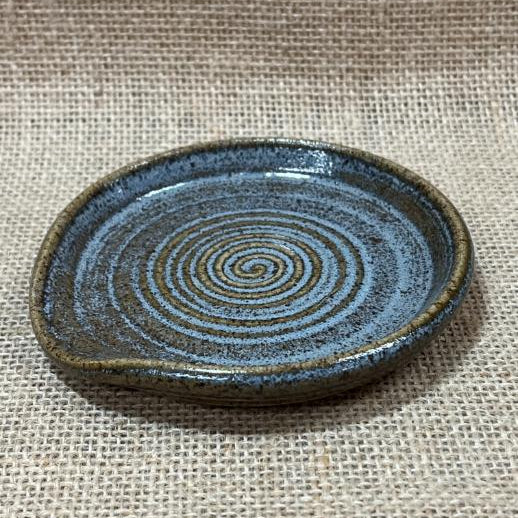 Ceramic plate with spiral design on a textured fabric background