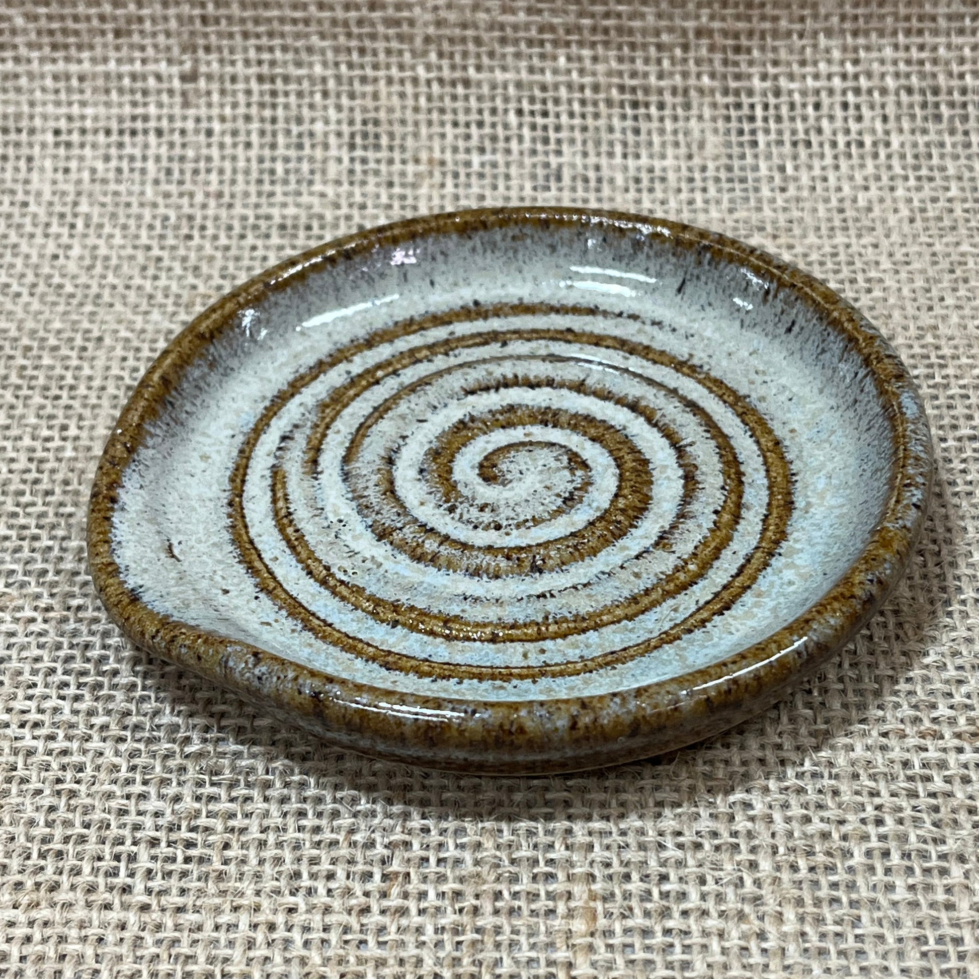 Ceramic button with concentric circle pattern on a textured fabric background